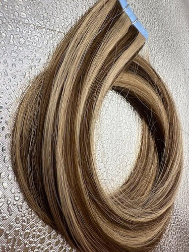 Tape-in hair extensions with natural blend of blonde and brown tones, showcasing smooth, straight remy human hair.