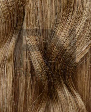 Close-up of smooth, natural-looking human hair extensions with blended highlights and soft waves.